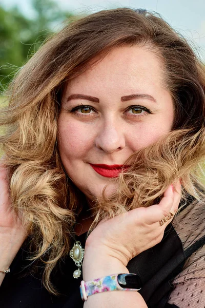 Artı yeşil buğday ve yabani haşhaş bir alanda siyah elbiseli bir kadın. Kilolu şişman kadın.