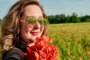 Artı yeşil buğday ve yabani haşhaş bir alanda siyah elbiseli bir kadın. Kilolu şişman kadın.