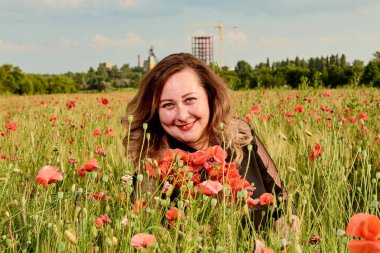 Artı yeşil buğday ve yabani haşhaş bir alanda siyah elbiseli bir kadın. Kilolu şişman kadın.