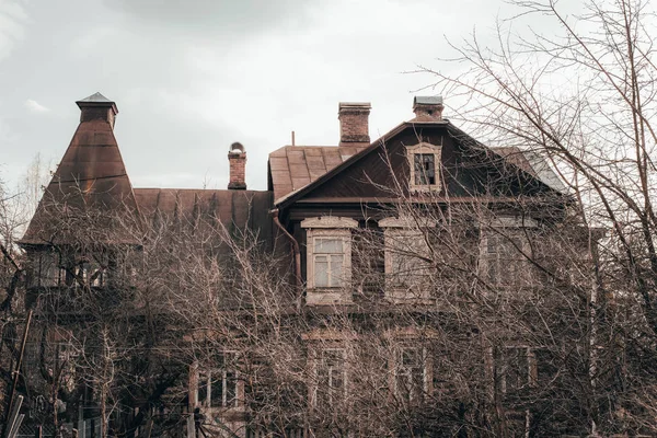 Velha mansão assustadora na floresta contra um céu cinzento — Fotografia de Stock