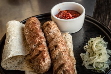 Soğan ve kırmızı domates soslu pide üzerine iki lula kebap