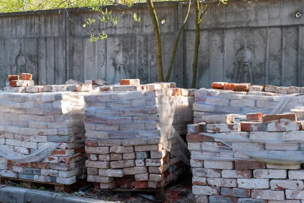 Alte Ziegel auf einem Holzrahmen gestapelt, teilweise mit Polyethylen überzogen — Stockfoto