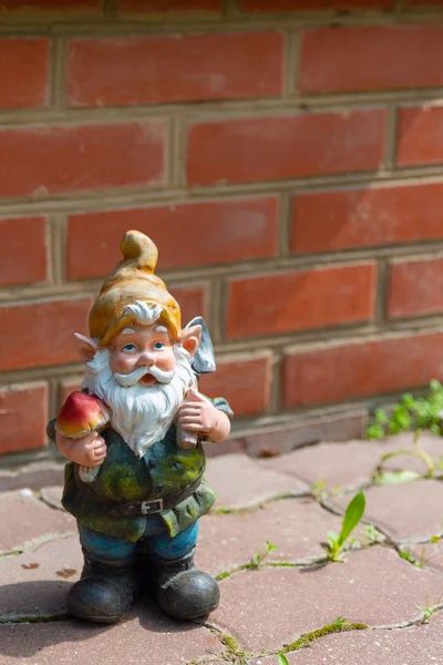 Kırmızı tuğla duvara karşı bir bahçe gnome figürü. 