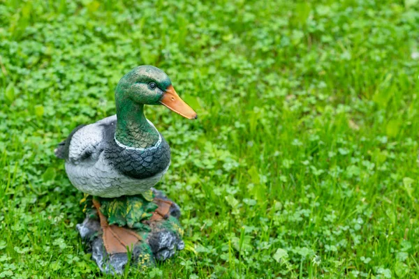Крупный план декоративной фигуры утки на фоне зеленой травы . — стоковое фото