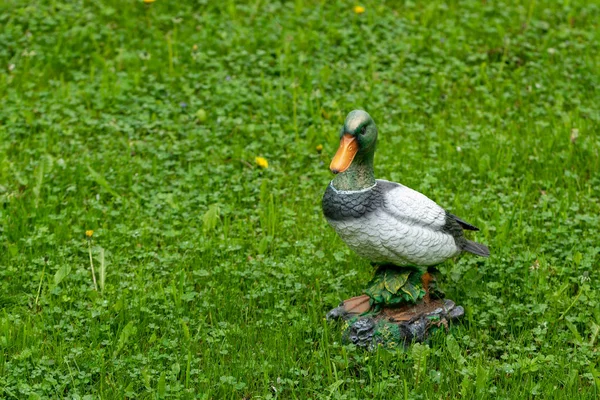 Декоративная фигура утки в саду на фоне зеленой травы — стоковое фото