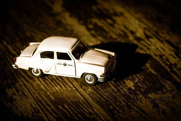 Modello giocattolo di una vecchia auto con un simbolo di taxi su uno sfondo di legno. Concentrazione selettiva. Copia spazio . — Foto Stock