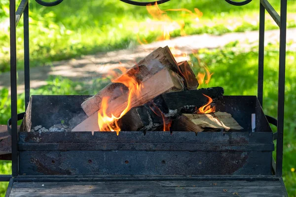 Firewood and branches in the old grill. Making a fire at a picnic. People burn firewood to make coal. Soft focus