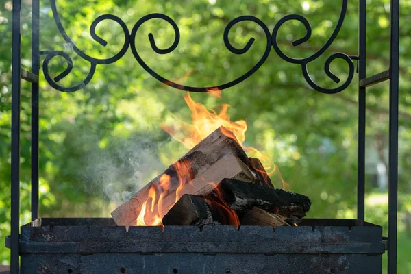 Drewno opałowe i gałęzie w starym grillu. Wykonywanie ognia na pikniku. Ludzie spalają Drewno kominkowe, aby węgiel. Miękka ostrość — Zdjęcie stockowe