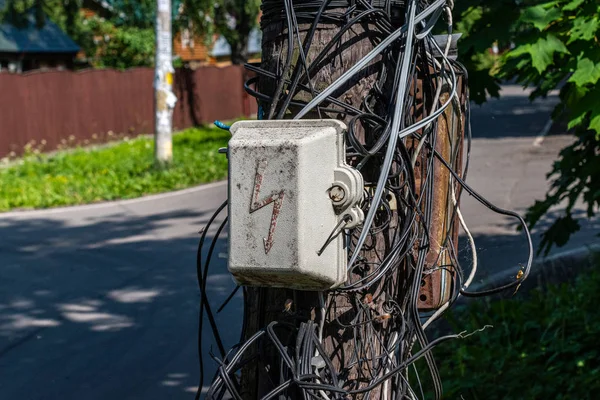 Eski ahşap bir sütun üzerinde karışık tellerin arka plan karşı eski elektroguard. Seçici odaklama.