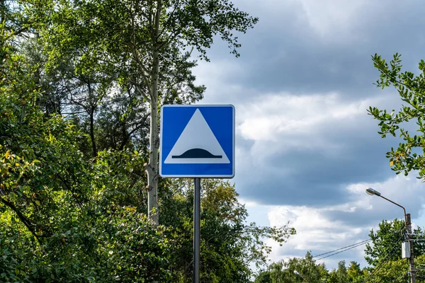 road sign speed bump on the background of cloudy sky and forest