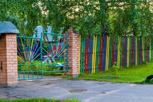 Crooked gate to the Playground. Multicolored fence and gate in t