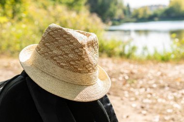 Bulanık arka planda sırt çantasında hasır şapka. Seyahat konsepti.
