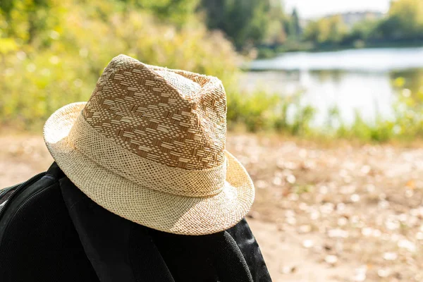 Straw hat on backpack on blurred background. Travel concept.