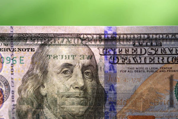 Hundred dollar bill on light against blurred green background