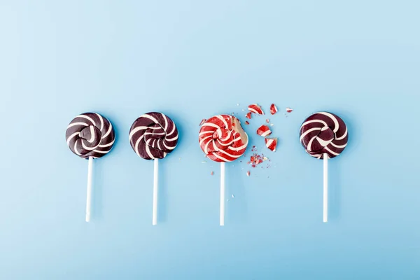 Colorful lollipops in a spiral on a blue background. Whole and crushed candy.