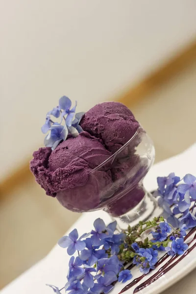 Deep purple ice cream scoops decorated with fancy flowers side view