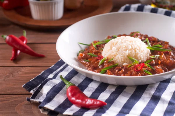 Chili con carne beyaz bir tabak içinde. Pişmiş kıyma, domates, biber, fasulye, sarımsak, soğan, kişniş