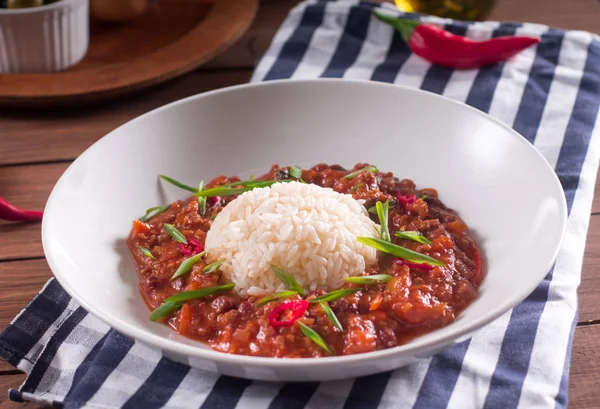 Chili con carne beyaz bir tabak içinde. Pişmiş kıyma, domates, biber, fasulye, sarımsak, soğan, kişniş