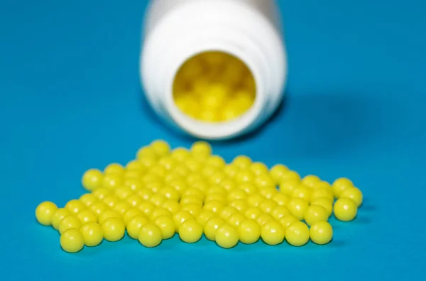 Round yellow vitamin C tablets on a blue background. Ascorbic acid close-up. Vitamin C for the treatment and prevention of colds. Virus protection.