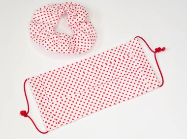 Beyaz arka planda eşleşen tokaları olan el yapımı pamuk kumaş yüz maskesi üzerine seçici bir odak noktası. Tükürük, öksürük, toz, kirlilik, virüs, bakteri ve COVID-19 'a karşı koruma. Moda aksesuarı olarak yüz maskesi.