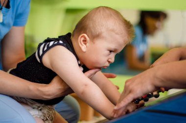 Çocuk terapi merkezinde fizyoterapi gören serebral felçli bir bebek. Özürlü çocuk egzersiz yaparak terapi görüyor. Çocuğun rehabilitasyon merkezinde kas dokusu terapisi var.
