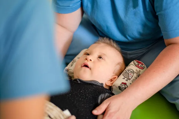 Çocuk terapi merkezinde fizyoterapi gören serebral felçli bir bebek. Özürlü çocuk egzersiz yaparak terapi görüyor. Çocuğun rehabilitasyon merkezinde kas dokusu terapisi var.