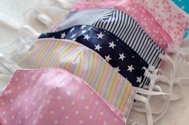 Çok renkli el yapımı pamuklu ve geri dönüşümlü yüz maskelerine odaklan. Üst Manzara. Tükürük, öksürük, toz, kirlilik, virüs, bakteri, COVID-19, koronavirüs.