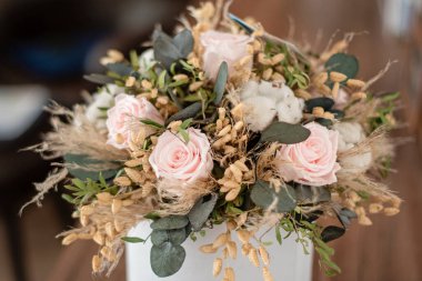 Uzun süreli çiçek süslemesi. Kurutulmuş çiçeklerle korunmuş güller. Yakın plan. Dekoratif bitkilerden yapılmış ev dekorasyonuna odaklan. Ebedi, dengeli, gül çiçeği.