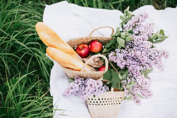 Cesta de picnic con bebidas, frutas y flores sobre hierba verde — Foto de Stock