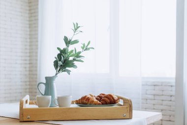 Mutfakta ahşap masa üzerinde duran kruvasan ile Plaka.