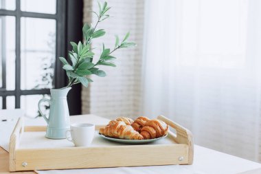 Mutfakta ahşap masa üzerinde duran kruvasan ile Plaka.