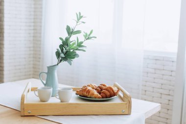 Mutfakta ahşap masa üzerinde duran kruvasan ile Plaka.