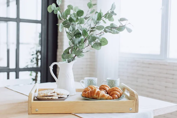 Placa con croissants de pie sobre mesa de madera en la cocina . — Foto de Stock