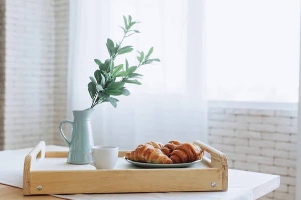 Placa con croissants de pie sobre mesa de madera en la cocina . — Foto de Stock