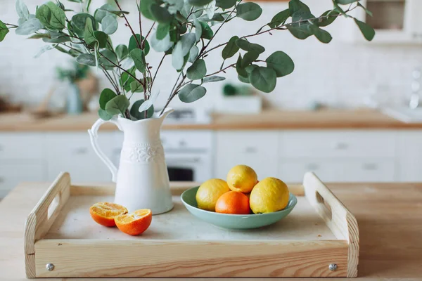 Placa con cítricos de pie sobre mesa de madera en la cocina — Foto de Stock