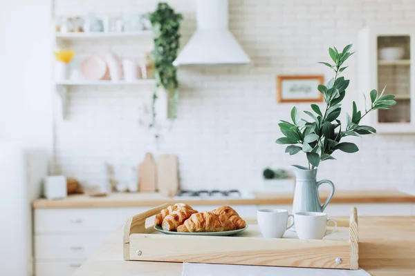 Placa con croissants de pie sobre mesa de madera en la cocina . — Foto de Stock