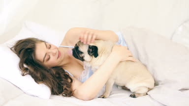 Kadın ile pug köpek yatakta sarılma. Video görüntüleri
