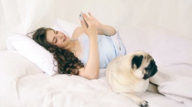 Yatakta kullanarak cep telefonu sosyal medya. Komik pug köpek kadınla. Video görüntüleri