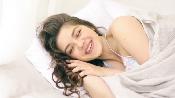 Boldog, mosolygós nő az ágyban. Napsütéses reggel. Videofelvétel — Stock videók