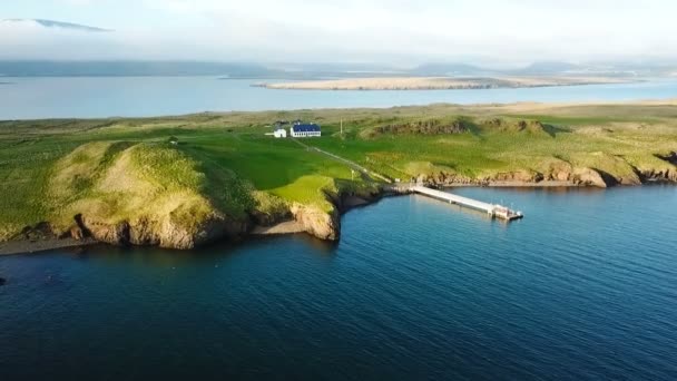 Casa en la isla Reikiavik Islandia. Vídeo aéreo de la parte superior. Agua del océano. montañas en el fondo. pequeña casa en la isla con muelle — Vídeos de Stock