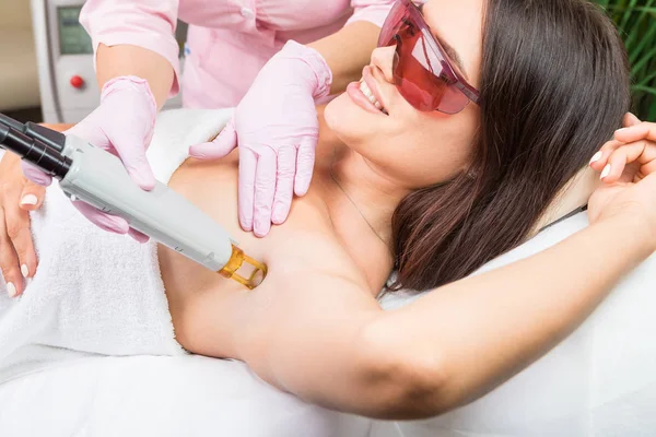 Oksel laser ontharing. Mooie lachende vrouw client in rode bril die procedure. — Stockfoto