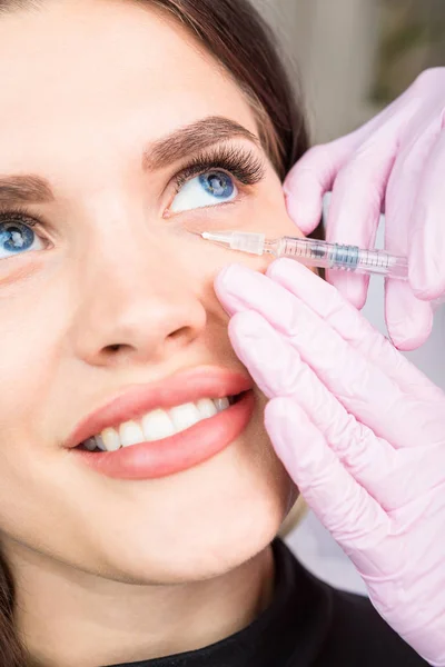 Injektion kosmetologi. Vårdar huden runt ögonen. Lyckligt leende avslappnad ögon patienten flicka. Professionell kosmetologi. Skönhet-hudvård — Stockfoto