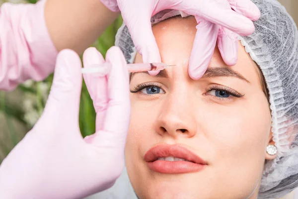 La chica tiene una inyección en la zona entre las cejas. paciente de la clínica de cosmetología. Tratamiento antiarrugas Botox Dysport. Cuidado profesional de la piel — Foto de Stock