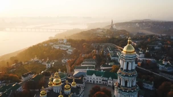 Kiyv ウクライナの首都。キエフ ・ ペチェールシク大修道院。空中ドローンのビデオ映像。ライダー ドニプロ ビューと橋。霧と日の出の光。すばらしい眺め。黄金色の太陽 — ストック動画