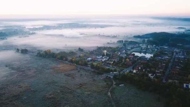空中录像雾蒙蒙寒冷的早晨乡村。小而富有的村庄, 周围环绕着雾蒙蒙的山谷和田野。道路。无人机摄像头顶部视图 — 图库视频影像