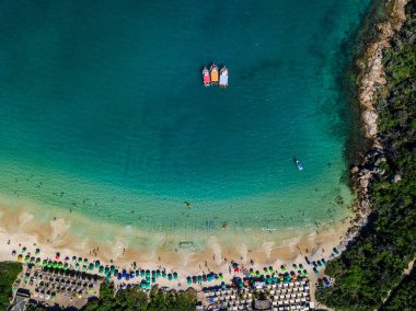 üç tekne kıyıda hazır. Plaj şemsiyeleri ve güneşlenenbirileri varsa. Yaz plaj Prainhas Pontal de Atalaia Arraial musun Cabo Rio de Janeiro Brezilya devlet.