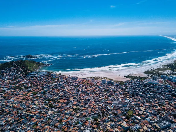 Brazilian small beautiful City Arraial do Cabo. Drone aéreo foto de cima da linha da cidade. Telhados vermelhos, ruas estreitas. Natureza brilhante oceano, montanhas e grande praia enorme no fundo — Fotografia de Stock