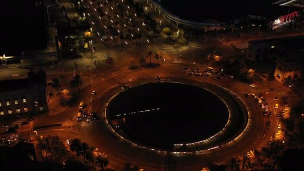 Vidéo aérienne nocturne du port de Barcelone et de la route avec trafic automobile. Caméra se déplaçant du rond point vers le haut — Video