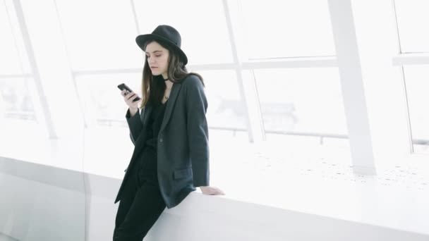 Usando telefone celular jovem mulher bonita no interior branco claro. Imagens de vídeo — Vídeo de Stock