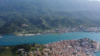 Poros. Yunanistan. Havadan 4k video görüntüleri. Kasaba tepelerini ve dağları aşağıda. İnanılmaz doğa ve rahat mimari. eski Avrupa şehrinin kiremitli çatıları